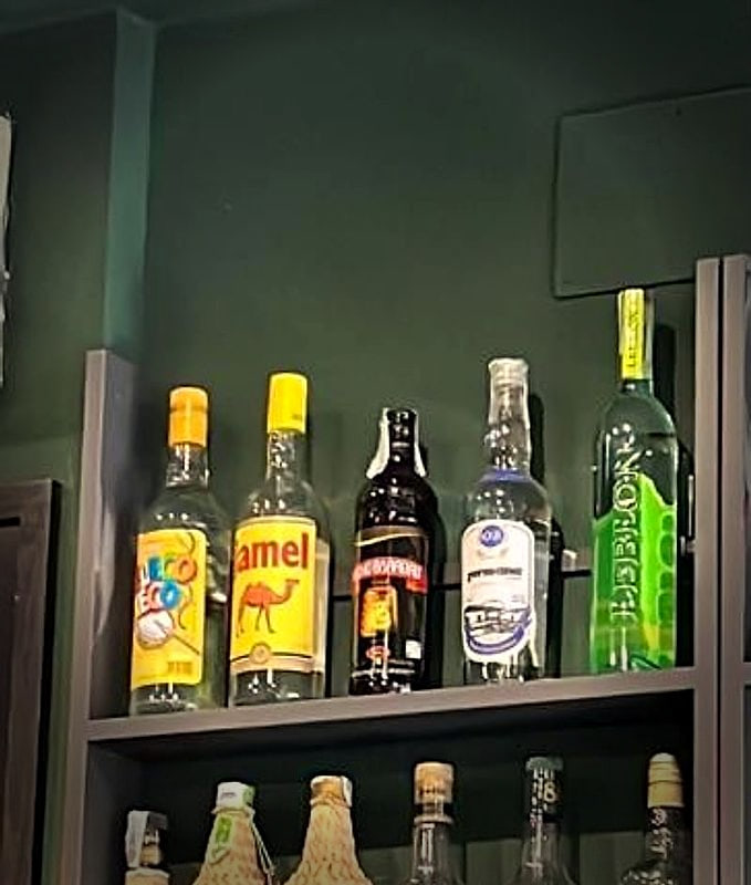 Le bottiglie di cachaça sullo scaffale, contro la parete verde