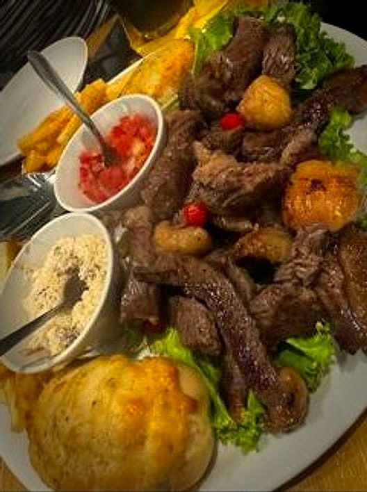 Il piatto di picanha visto dall'alto, con la farofa e il vinagrete nelle ciotoline