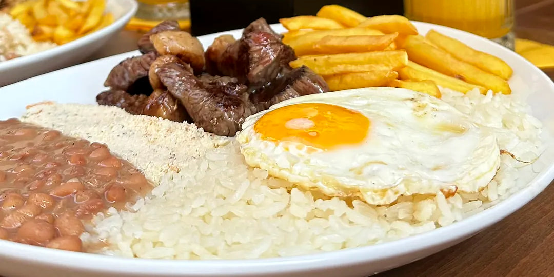 Il piatto da vicino: la farofa fra i fagioli e il riso, la carne e l'uovo al centro